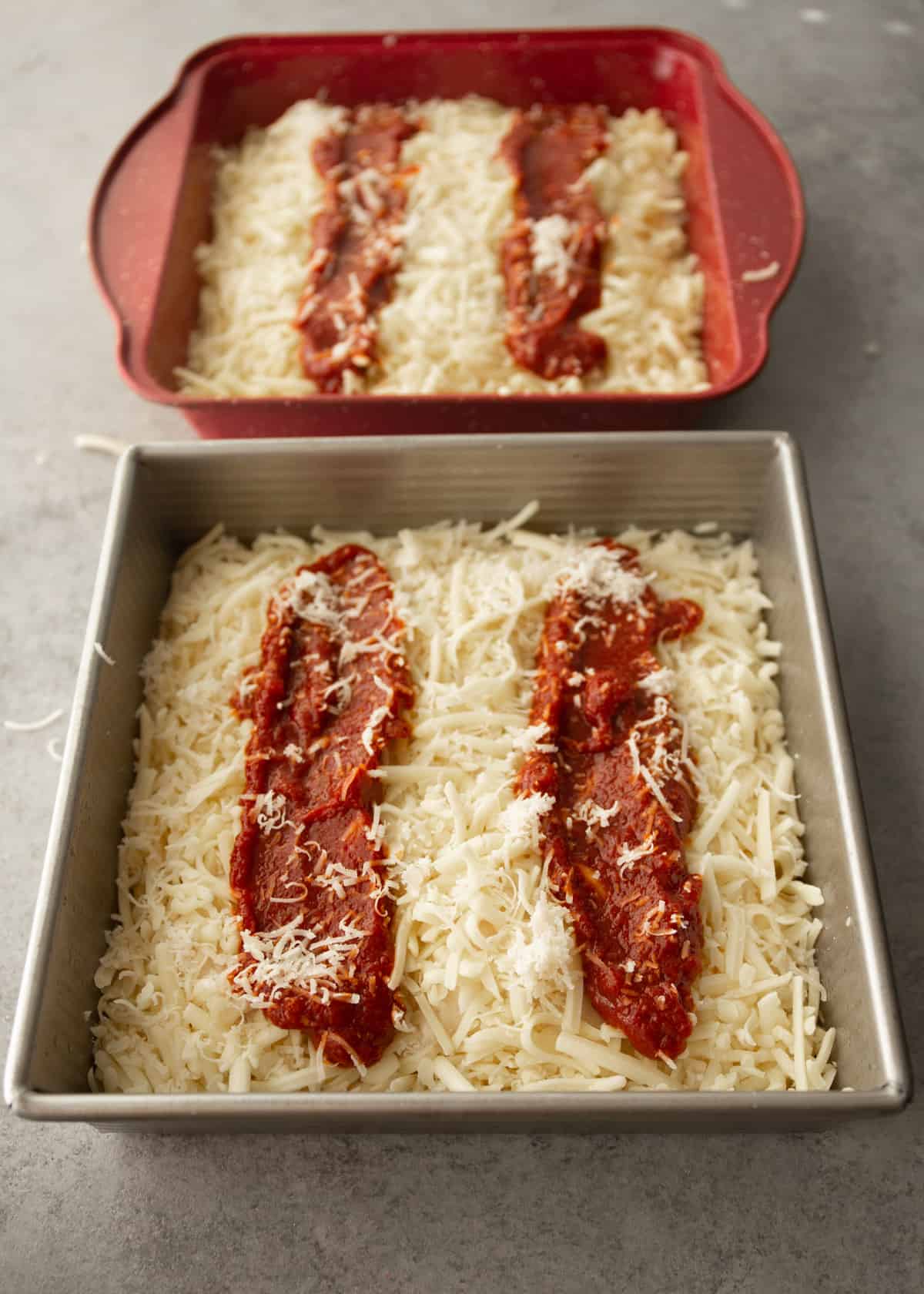 pizza dough, cheese and sauce in a square baking pan