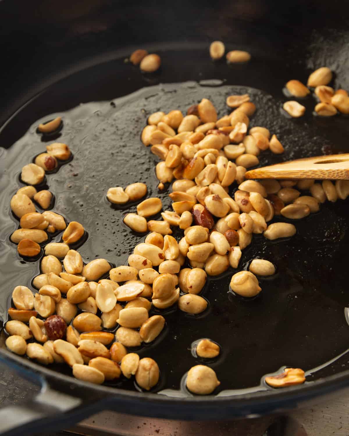 stirring peanuts in a cast iron skillet