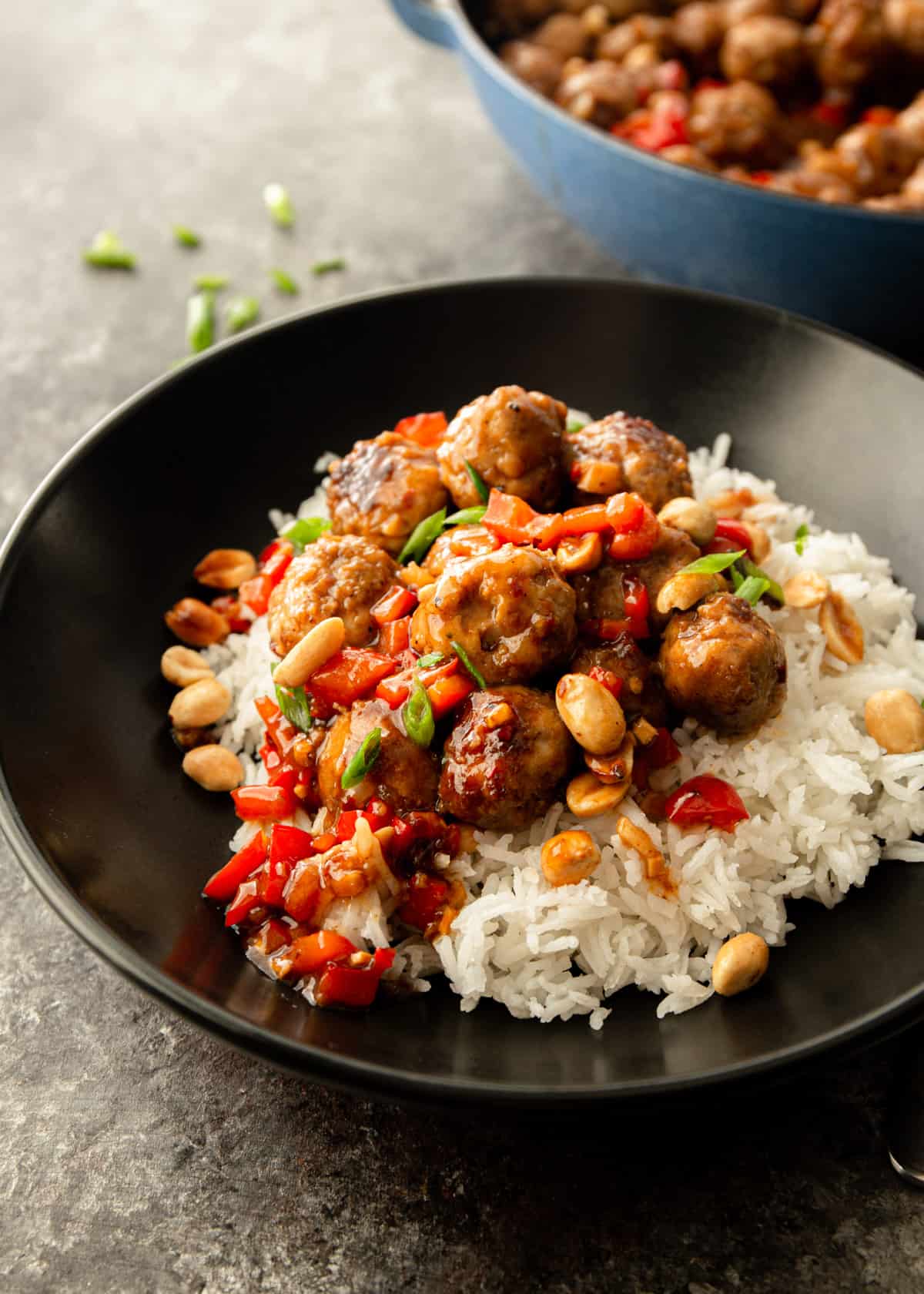 overhead image of meatballs over rice in a black bowl