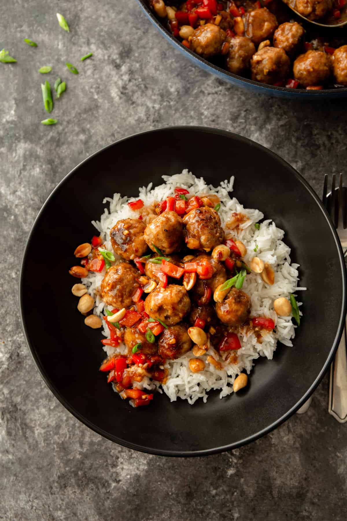 overhead image of meatballs over rice in a black bowl