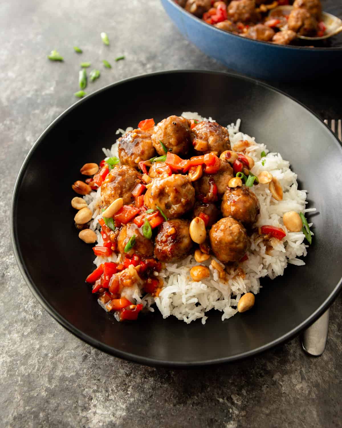 overhead image of meatballs over rice in a black bowl