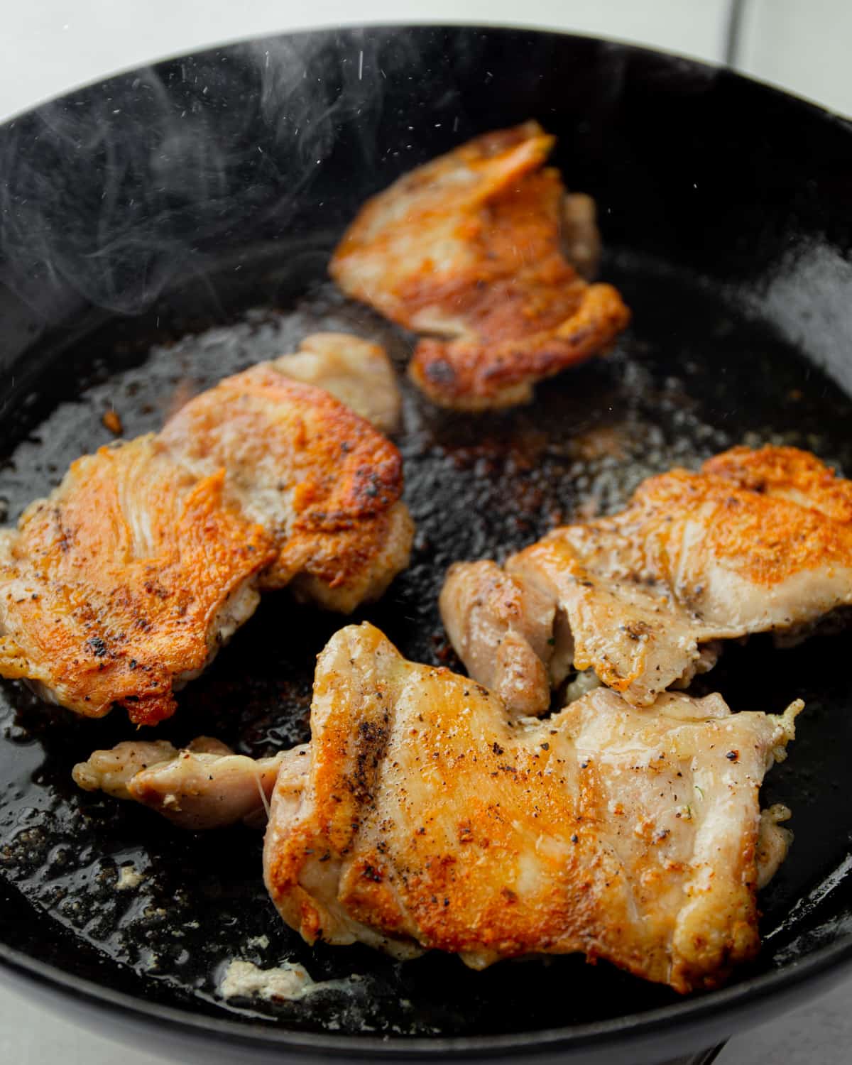 cooking chicken thighs cooking in a black dutch oven