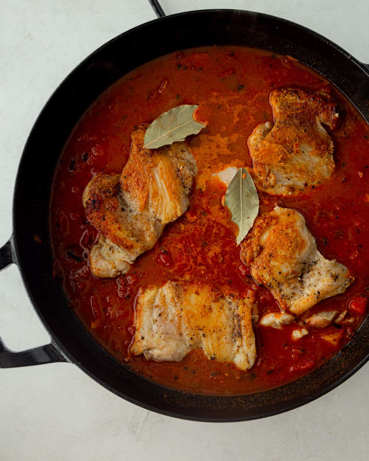 chicken and sauce in a black dutch oven