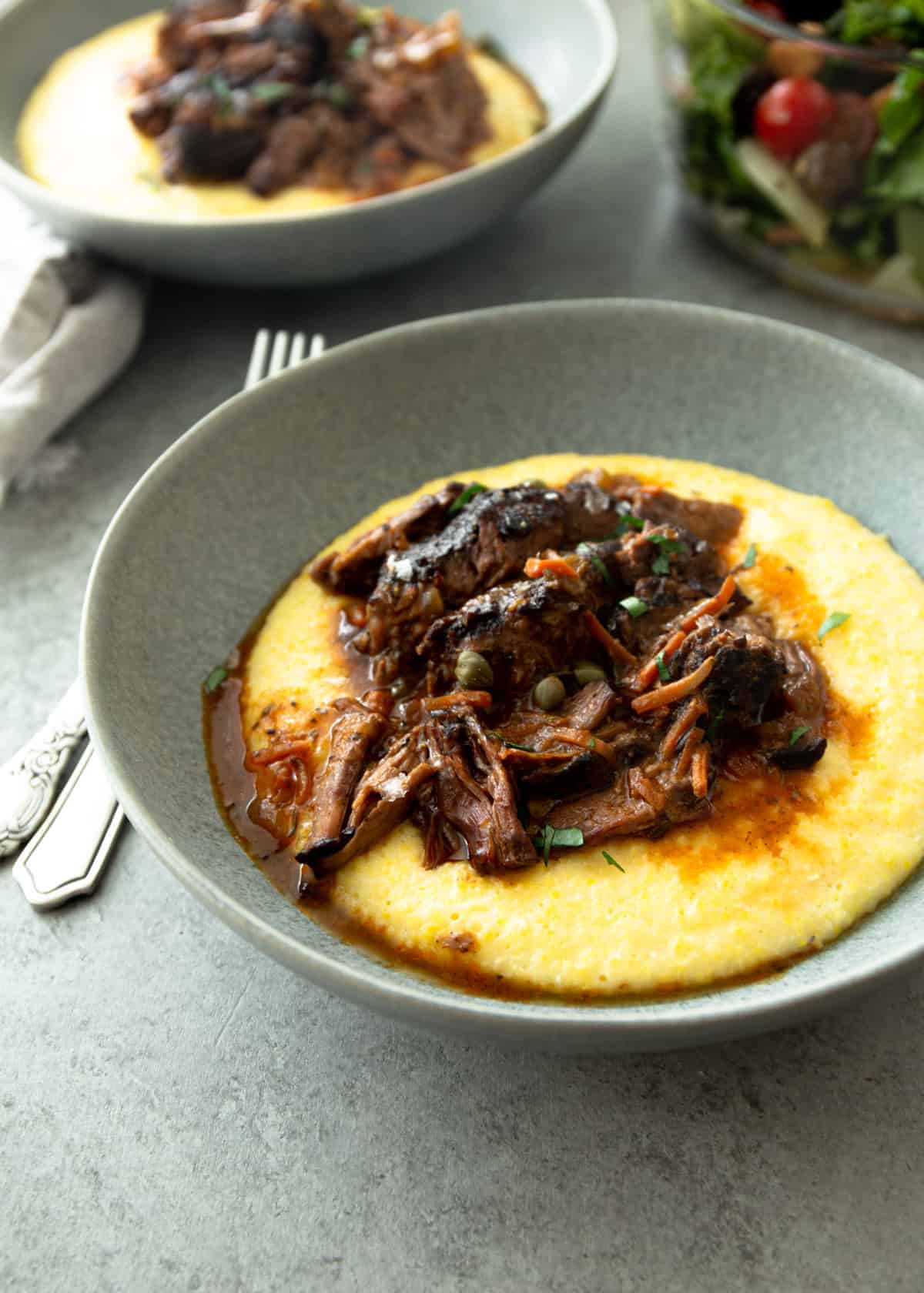 pot roast over polenta in a grey bowl