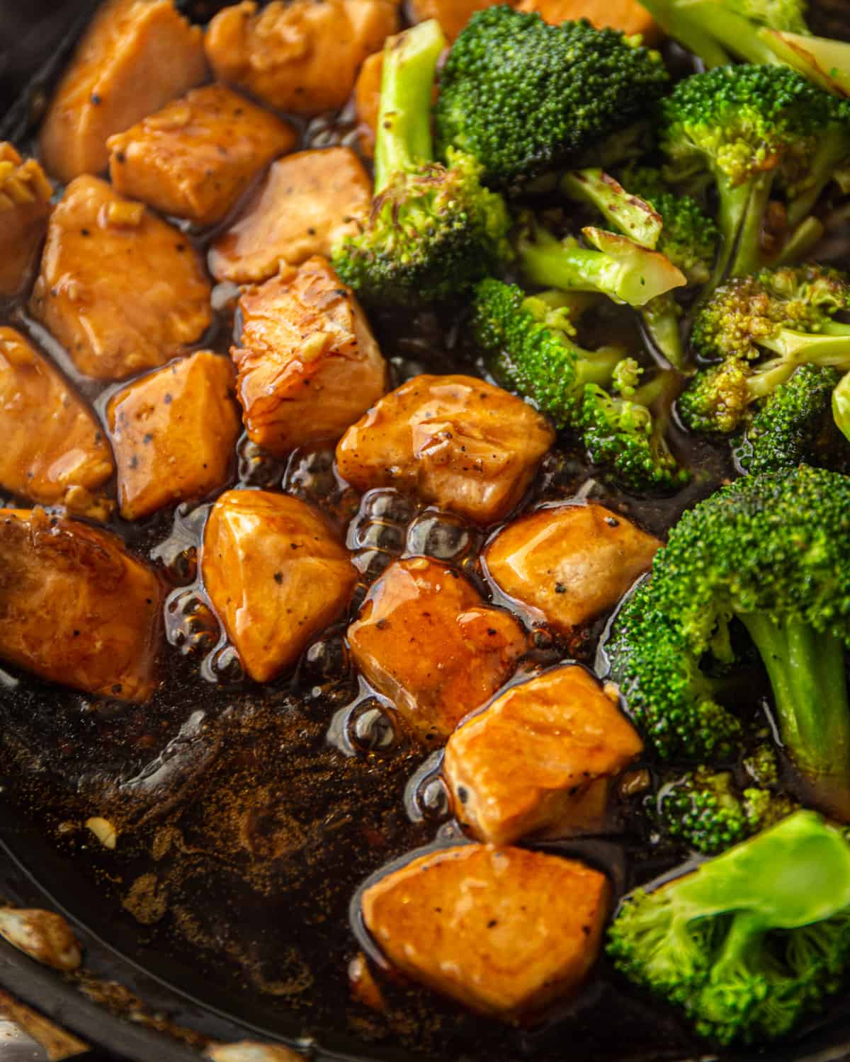 stirring salmon and broccoli in teriyaki sauce