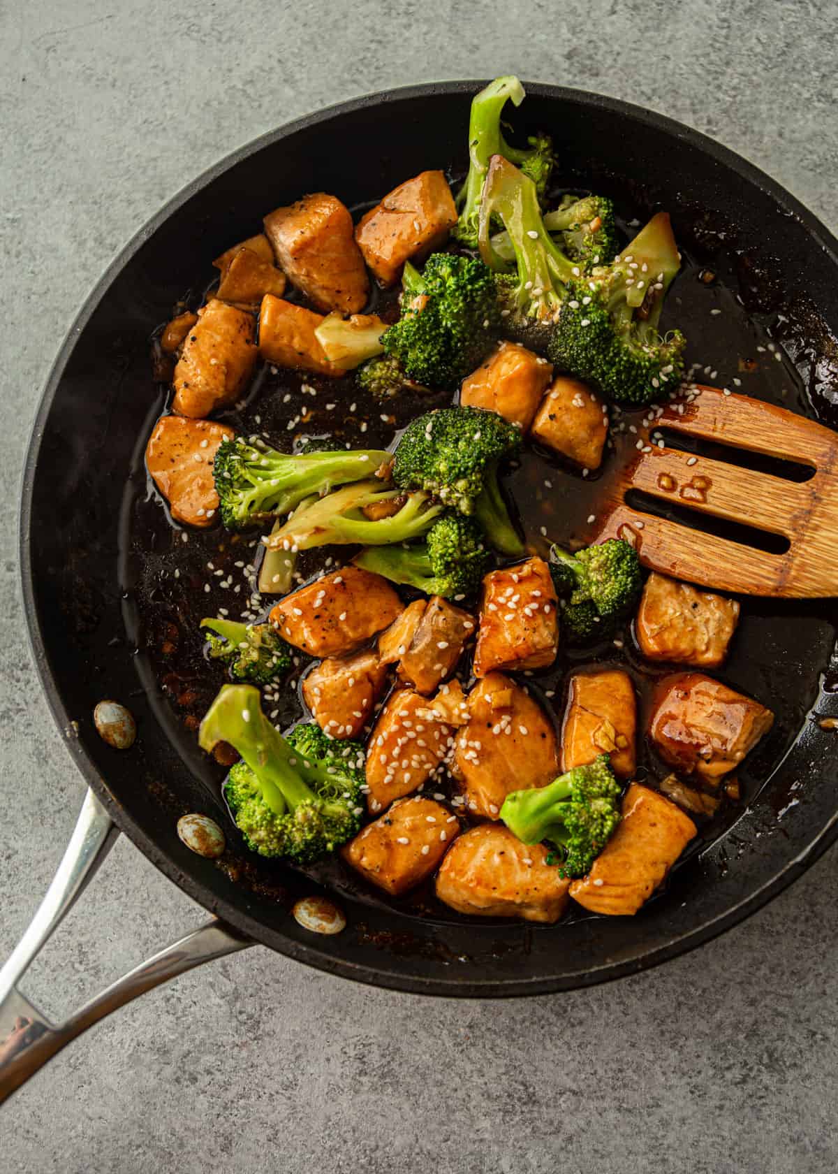 overhead image of stirring salmon and broccoli in a skillet