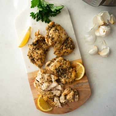 chicken thighs and lemon slices on a wooden cutting board