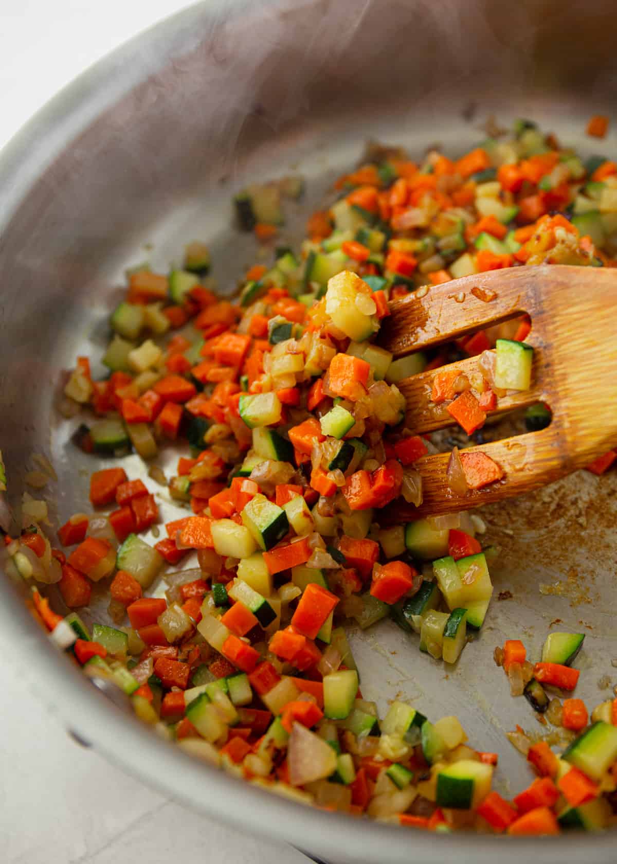 stirring diced vegetables in a skillet