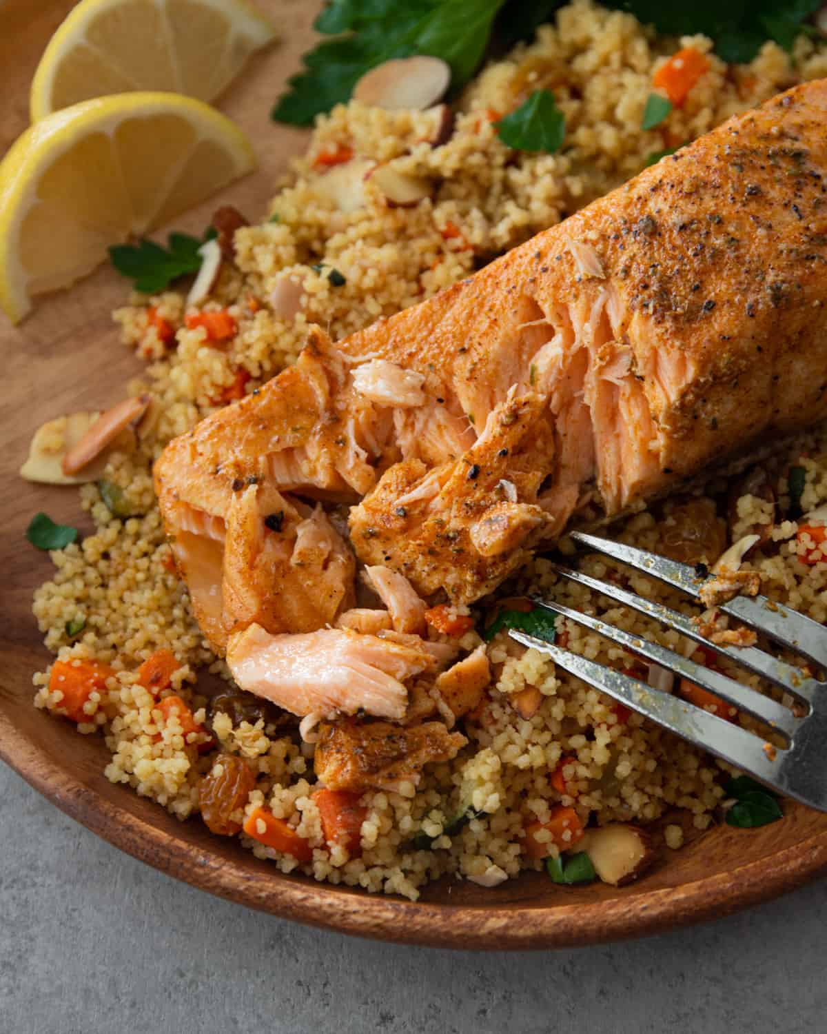 salmon and couscous on a wooden plate with a fork