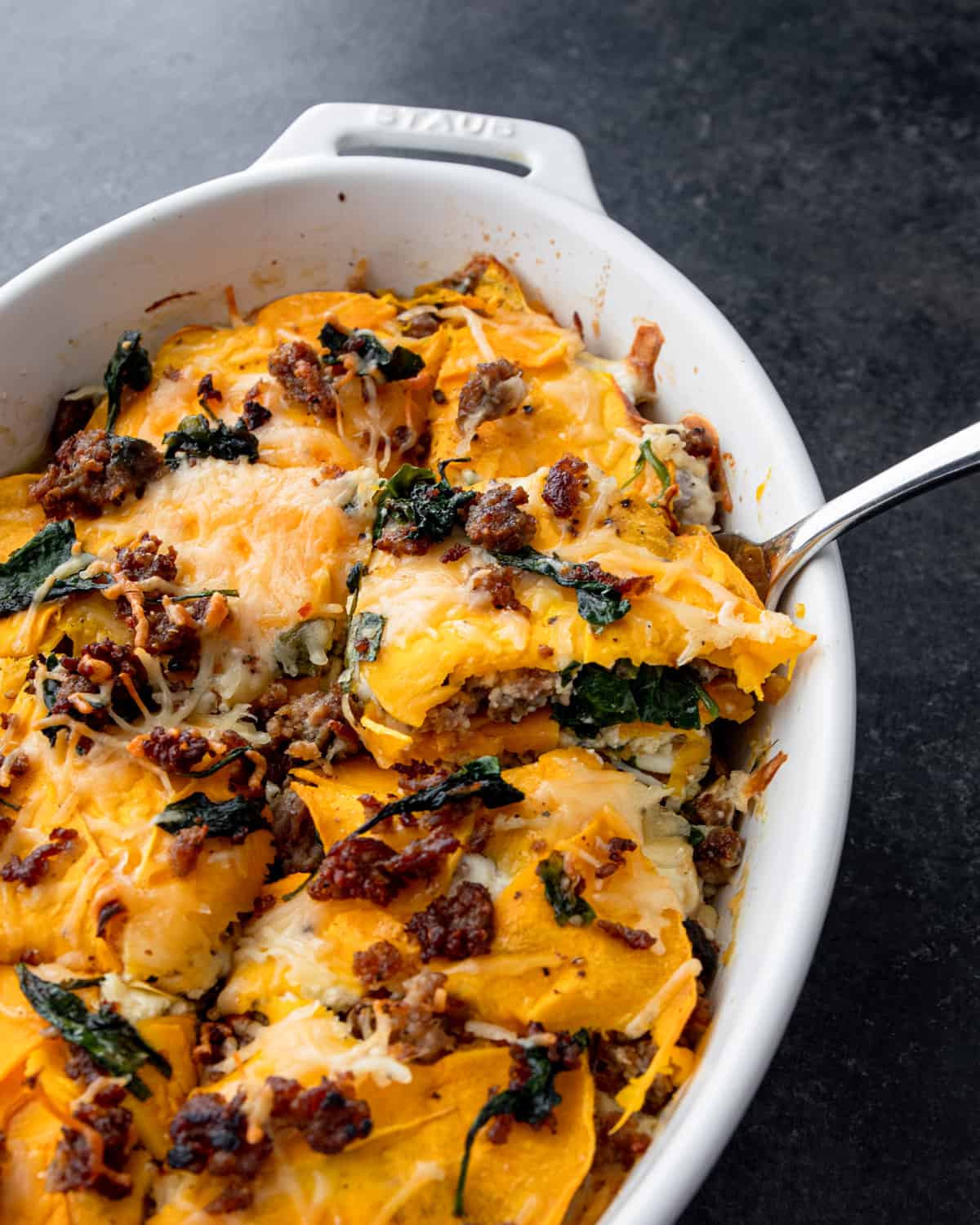 overhead image of a spoonful of butternut squash lasagna in a white baking dish