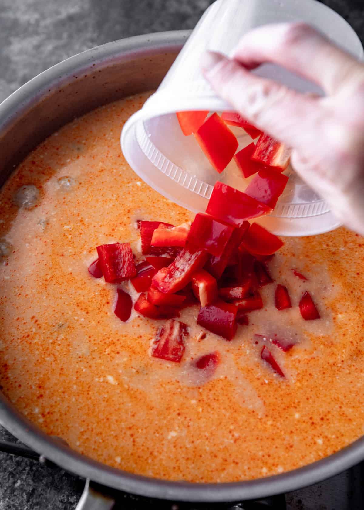 adding chopped bell peppers to curry