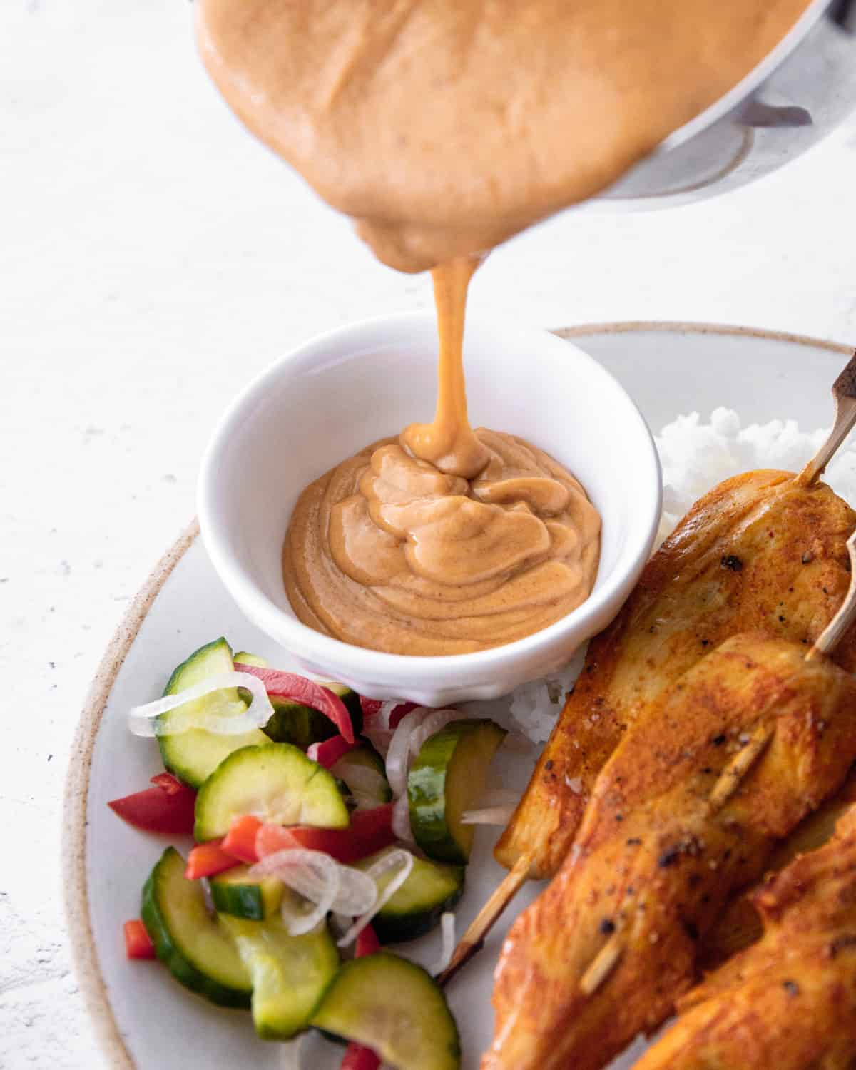 adding peanut sauce to a white ramekin 