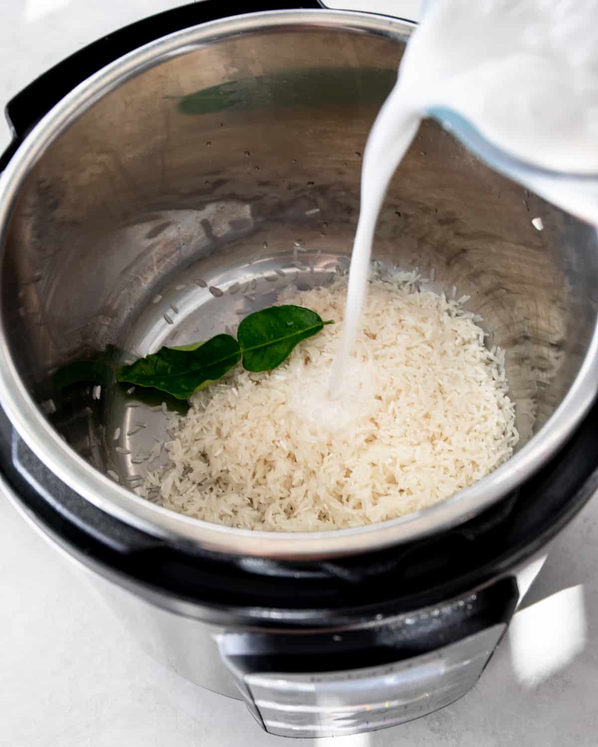 adding coconut milk to rice in an instant pot