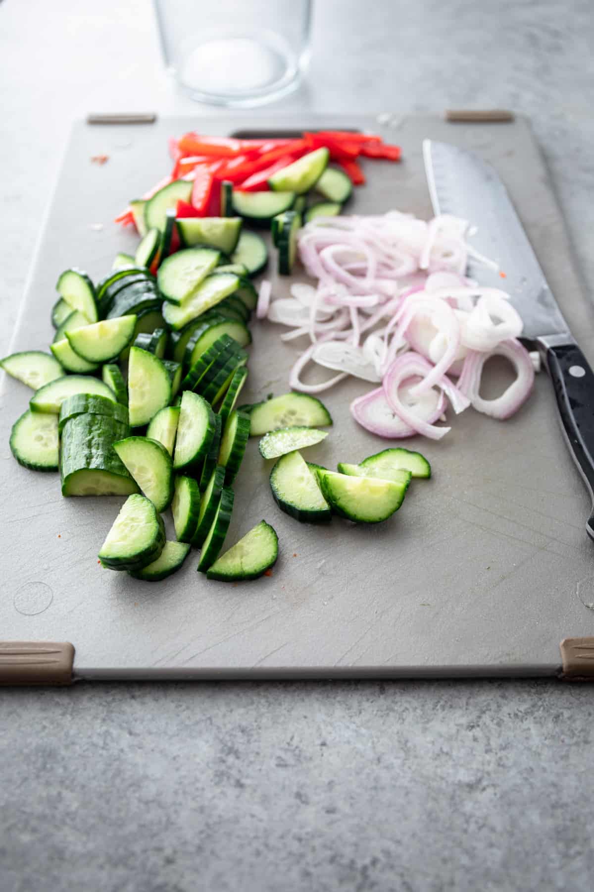 sliced cucumbers, onions and peppers on a cutting board