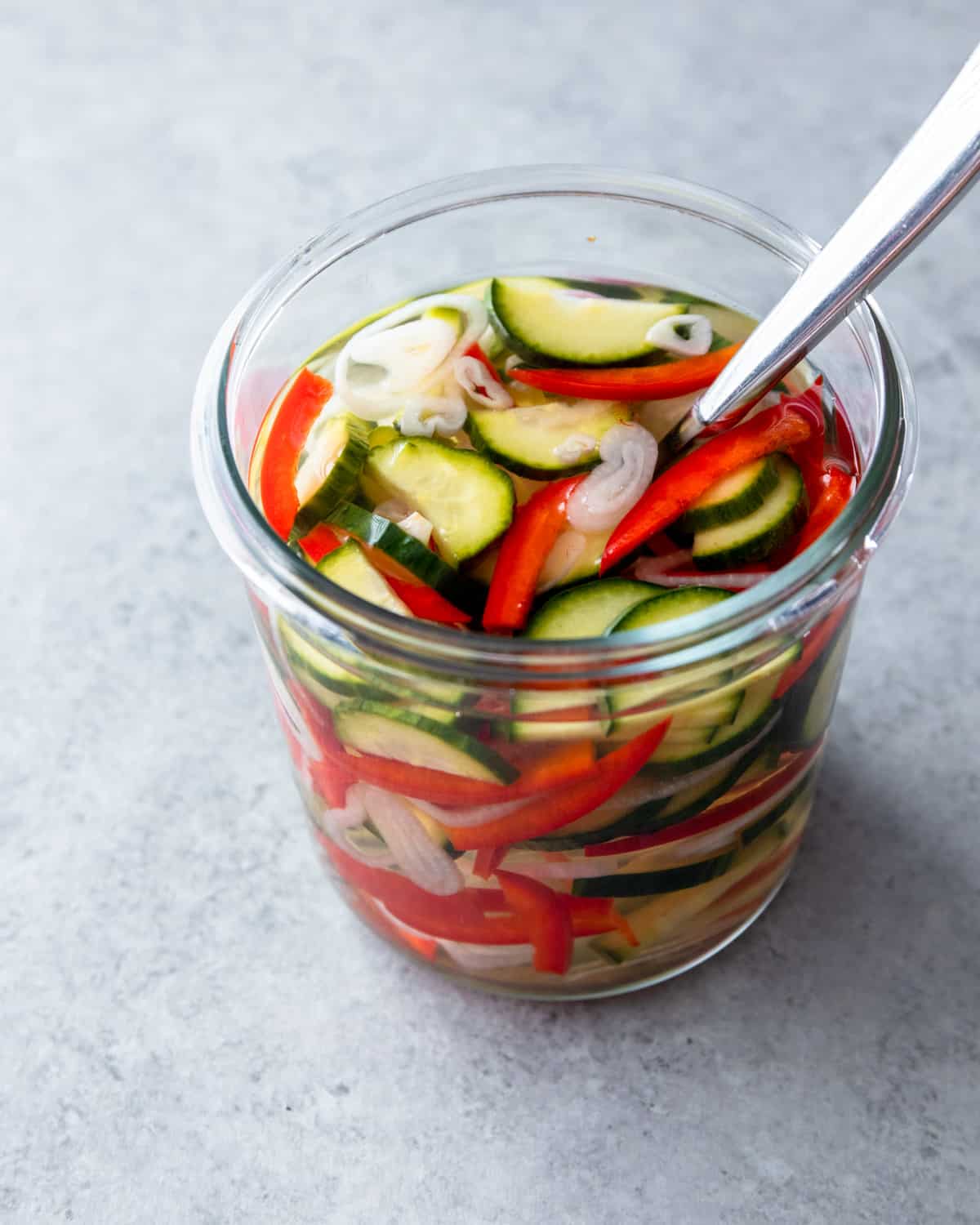 a spoon in a glass jar of pickles