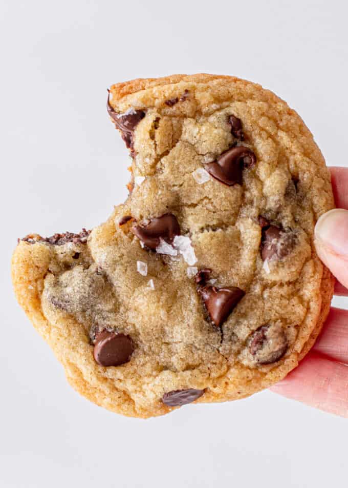 hand holding a chocolate chip cookie with a bite out of it