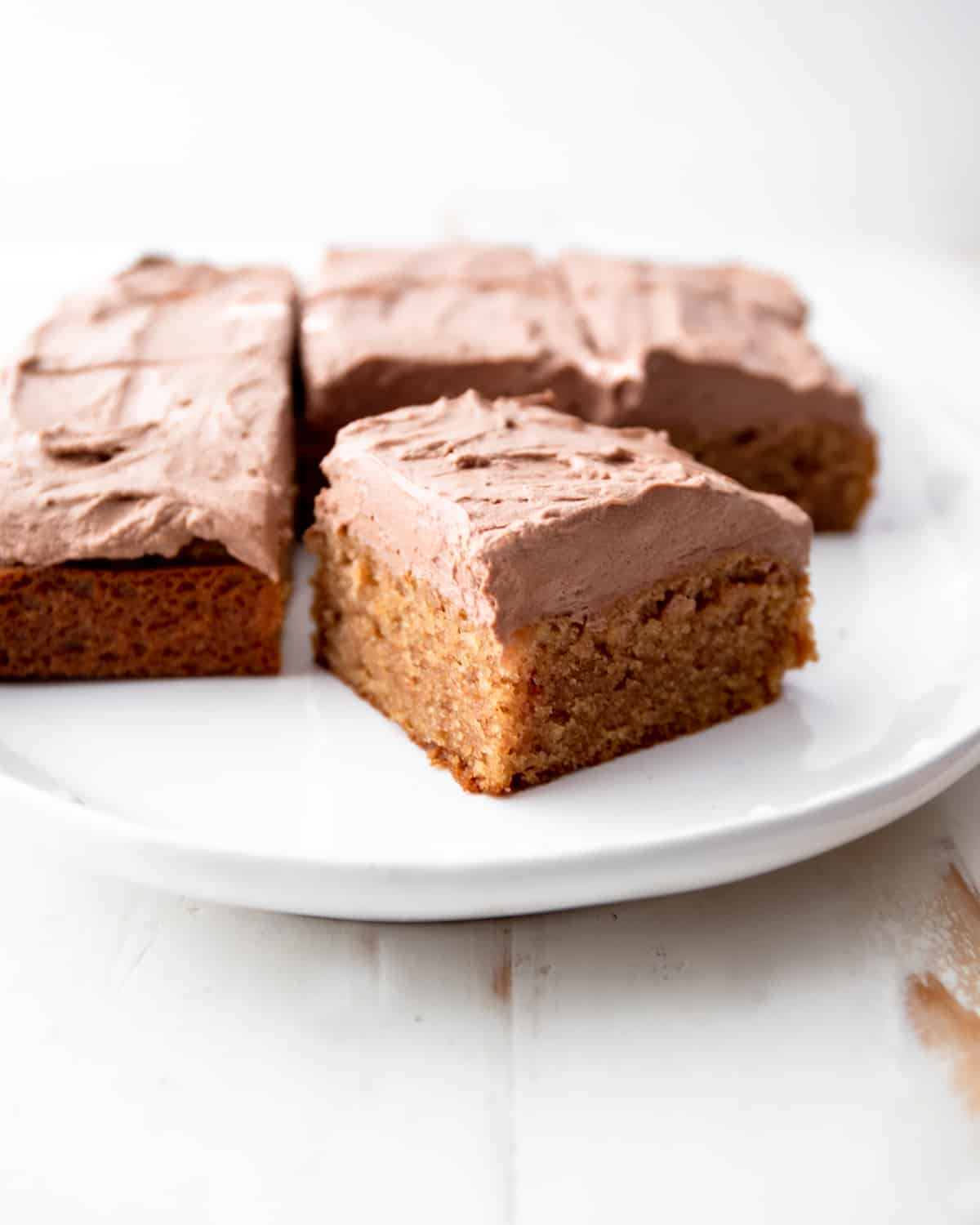 a square cake with chocolate frosting  cut into squares on a white plate