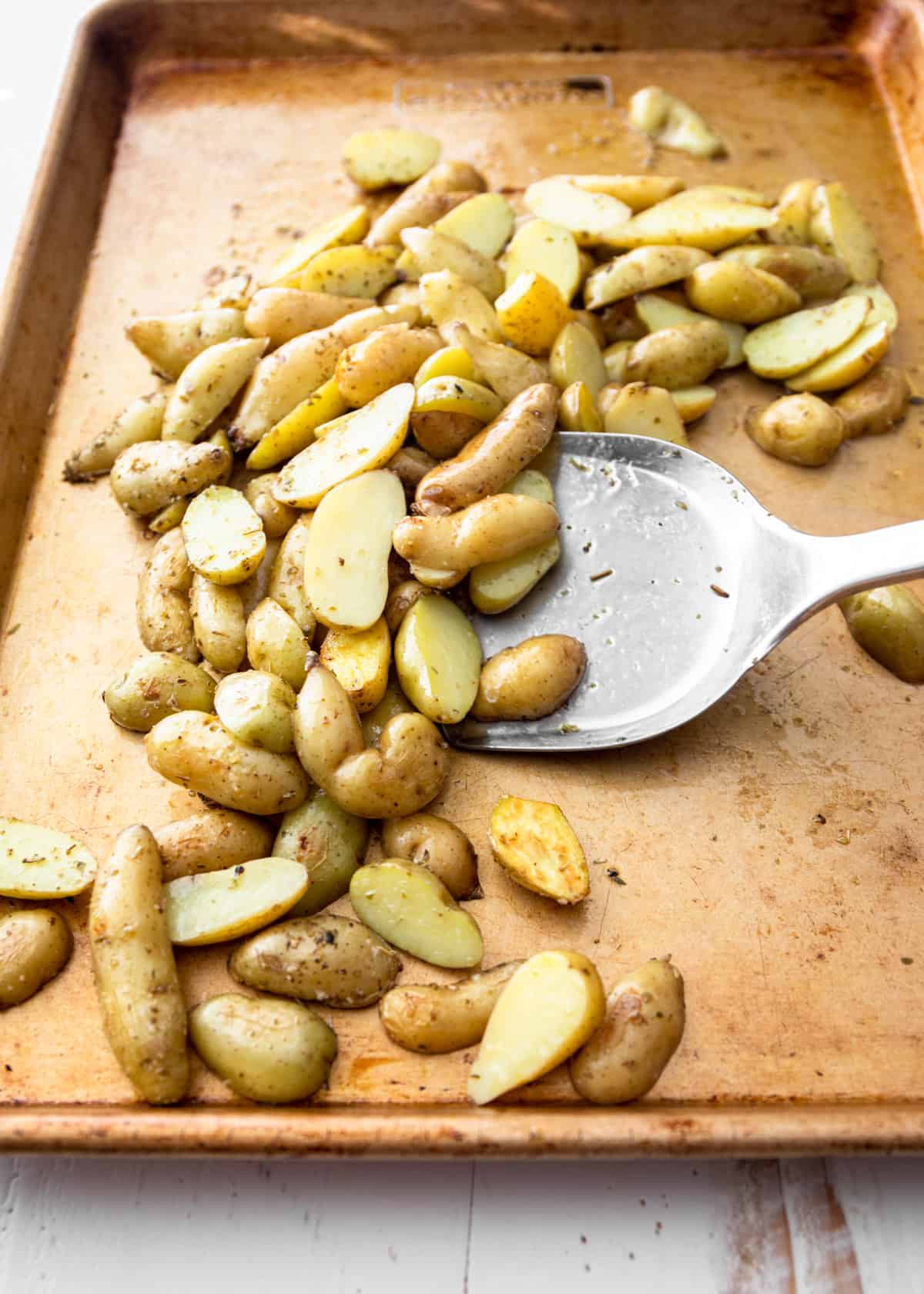 roasted potatoes on a sheet pan with a spatula