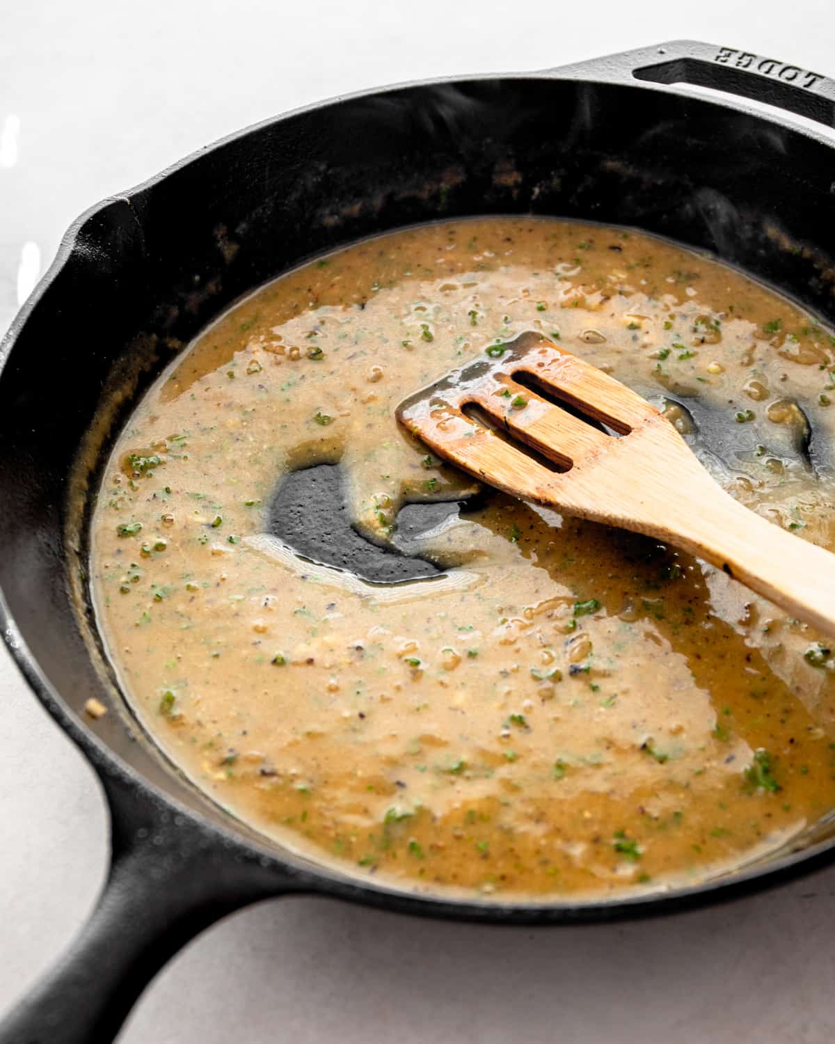stirring pan sauce in a cast iron skillet