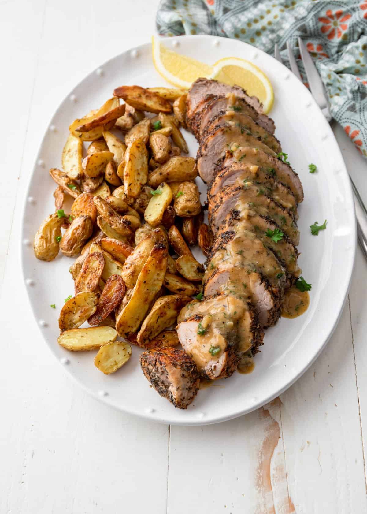 overhead image of pork tenderloin and potatoes on a white tray