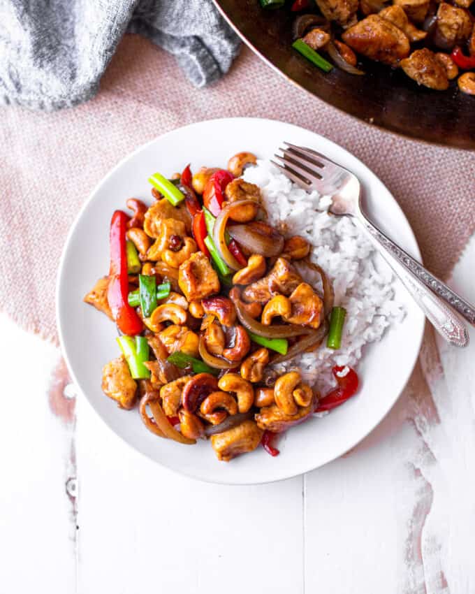 cashew chicken over rice on a white plate