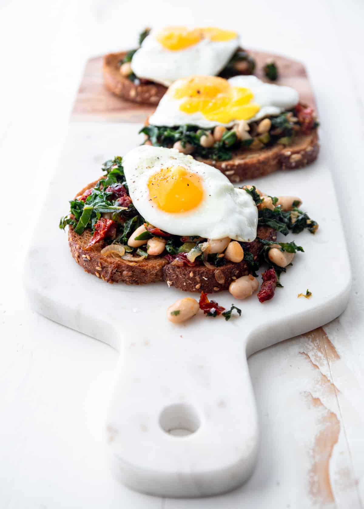 white beans and greens on toasted bread on a cutting board