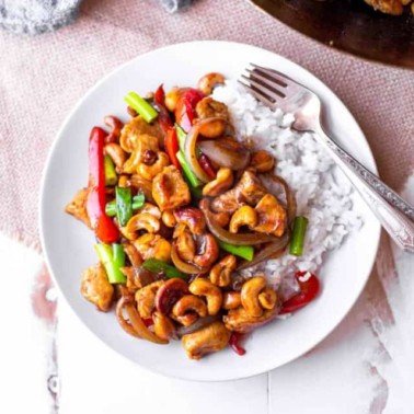 cashew chicken over rice on a white plate