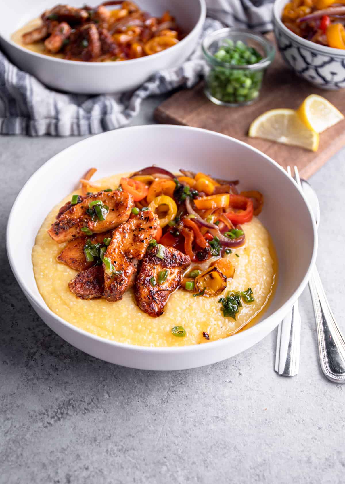 fish and peppers over polenta in a white bowl