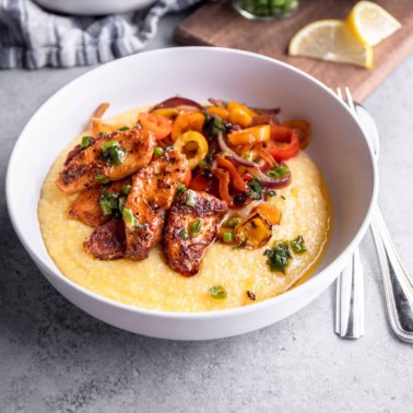 polenta, fish and peppers in a white bowl