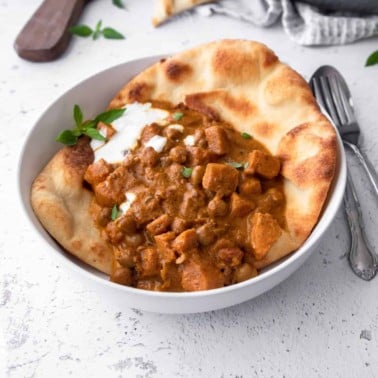 curry and naan in a white bowl