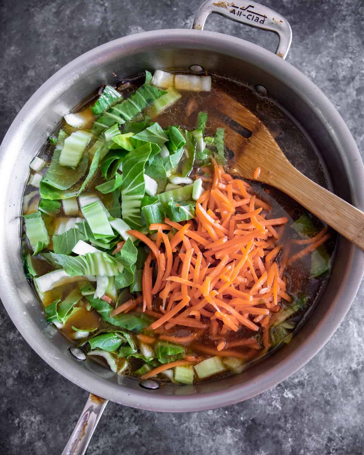 overhead image of stirring vegetables into broth in a saucepan