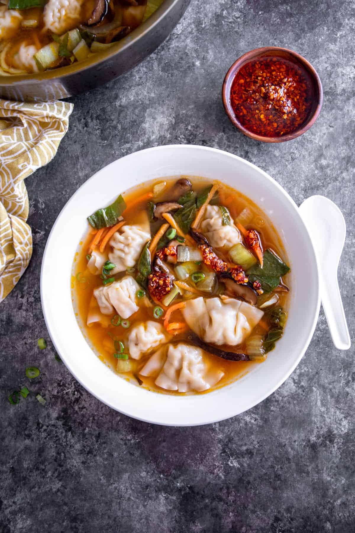 overhead image of wonton soup with vegetables in a white bowl