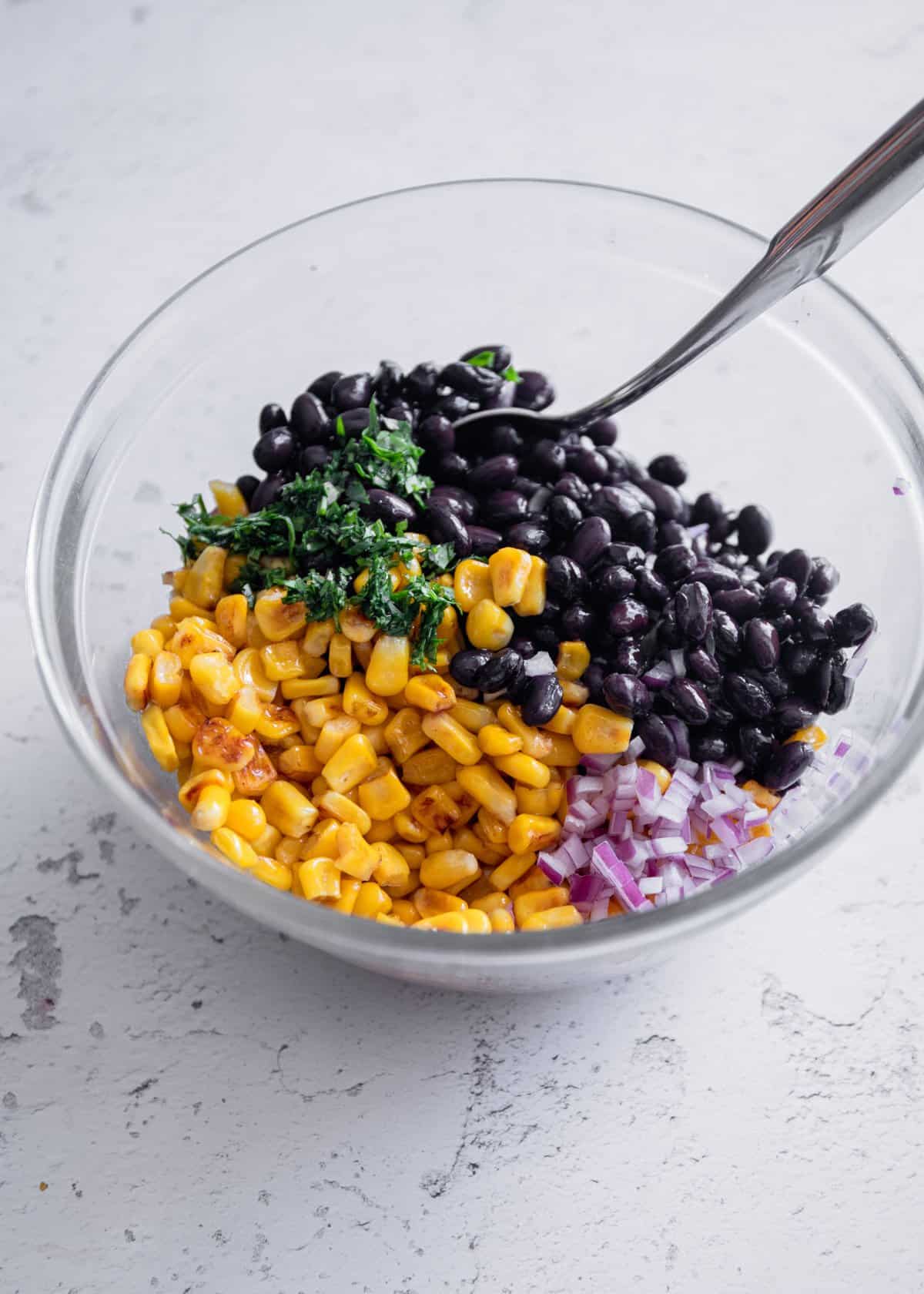 black beans, corn, onions and cilantro in a clear glass bowl