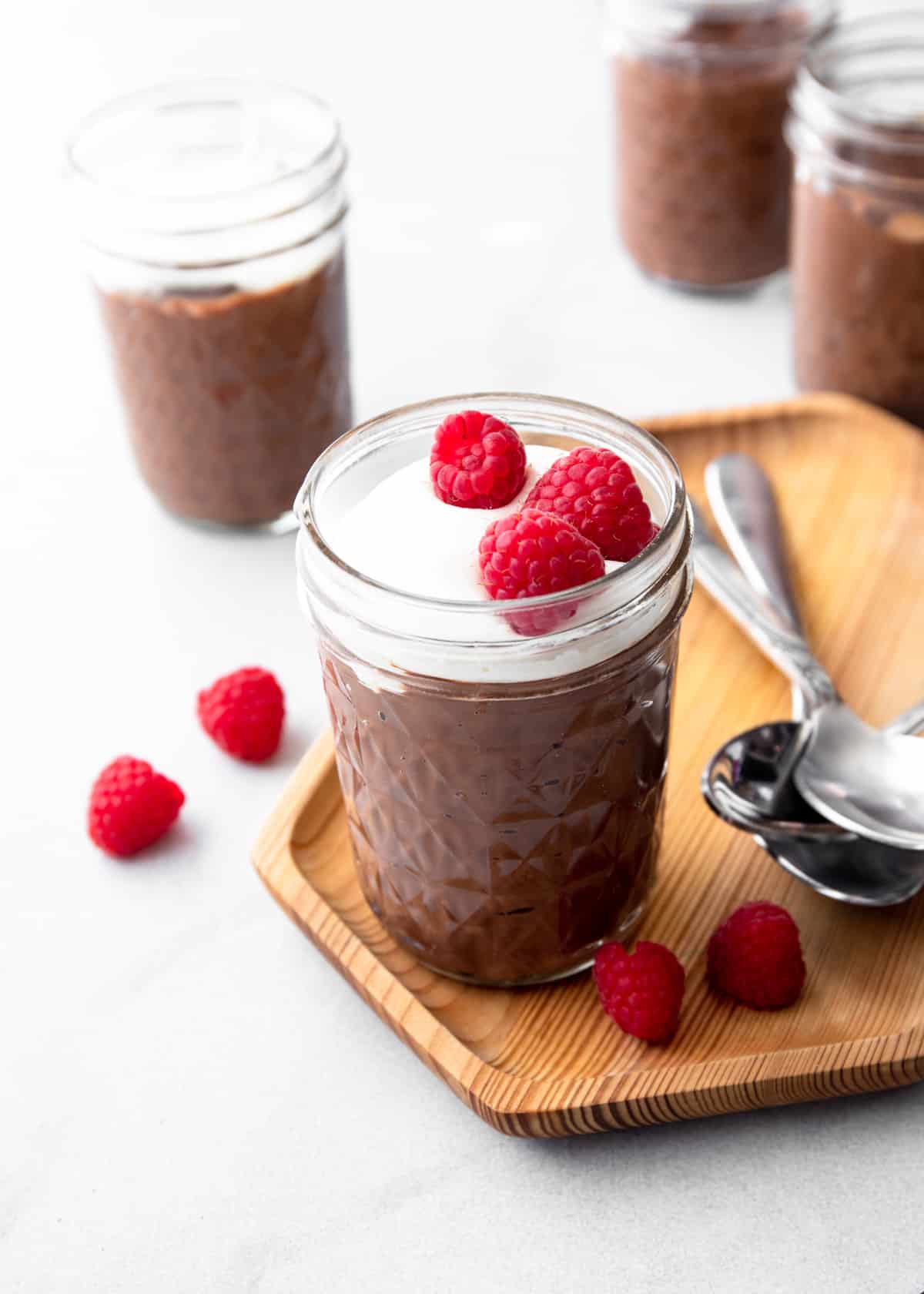 chocolate pudding topped with whipped cream in a small glass jar