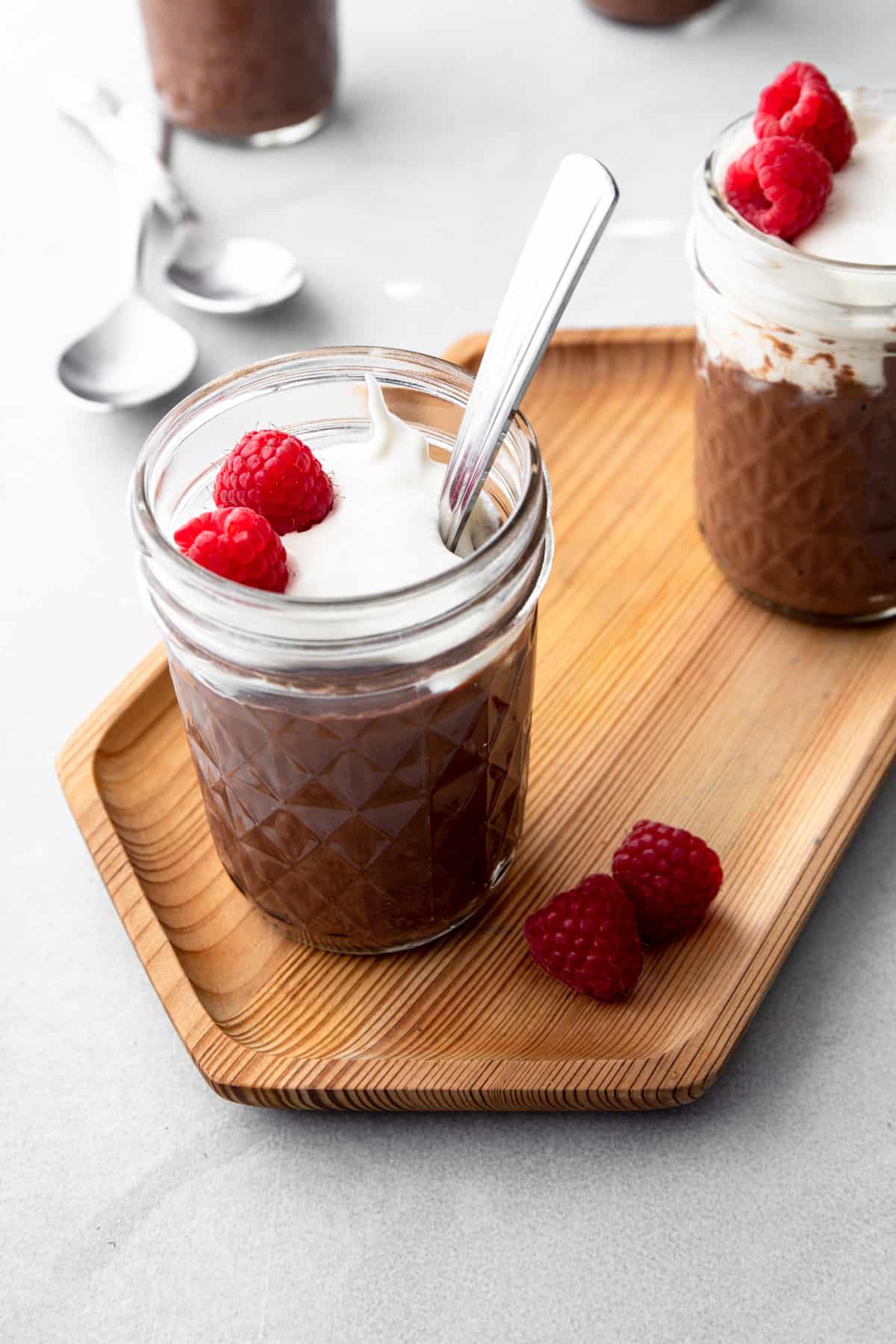 chocolate pudding in a small glass jar on a wooden tray