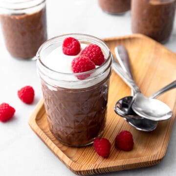 chocolate pudding with whipped cream and raspberries in a small glass jar