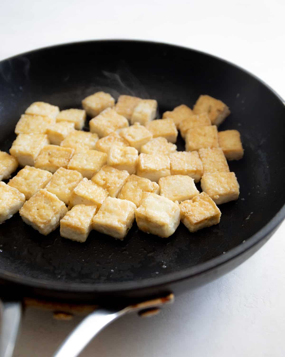 cooking cubes of tofu in a skillet