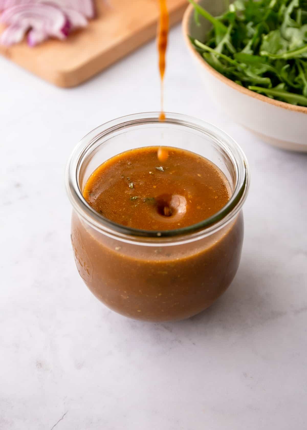 drizzling homemade vinaigrette into a small glass jar