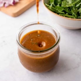 drizzling vinaigrette into a small glass jar