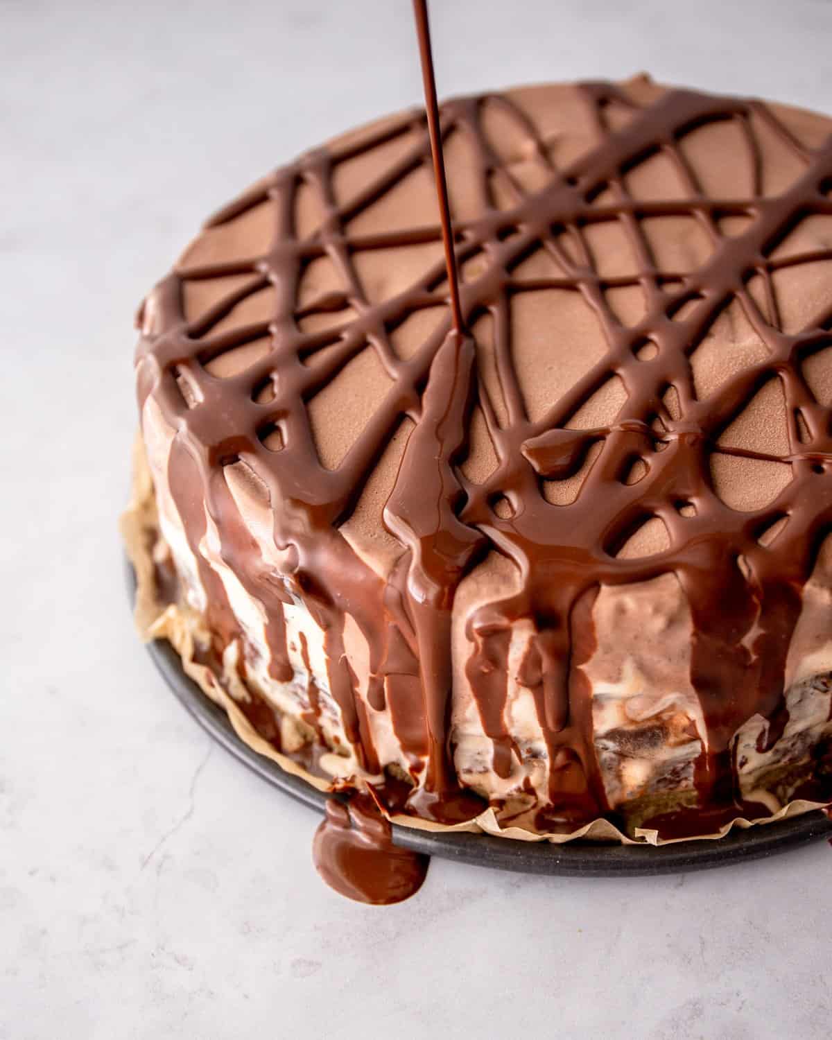 pouring chocolate syrup over the top of an ice cream cake