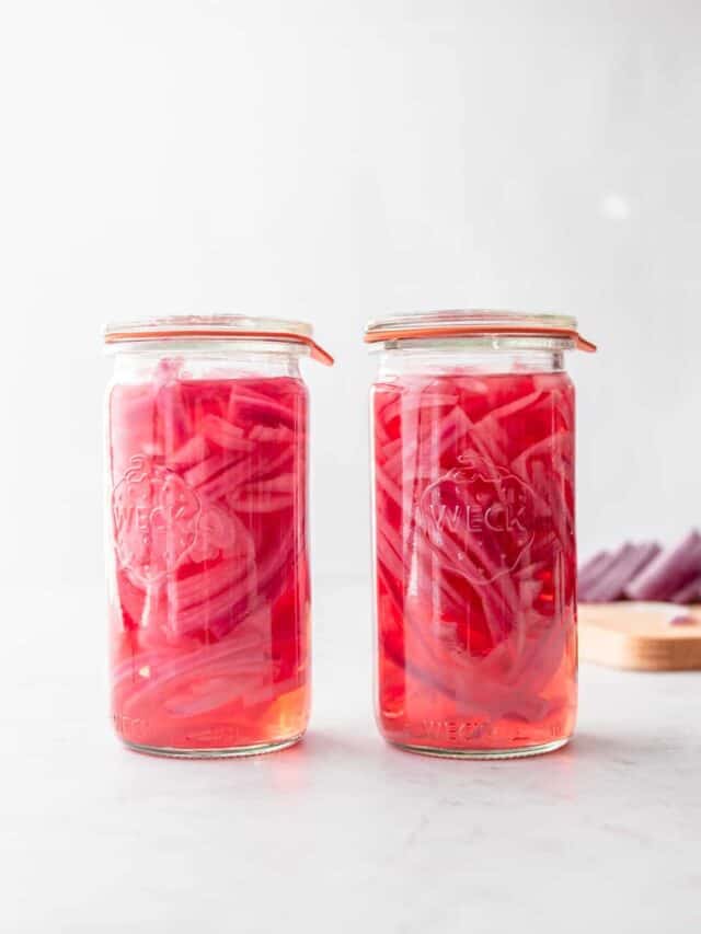 pickled red onions in glass jars on a grey countertop