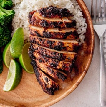 sliced chicken with rice and broccoli on a wooden plate