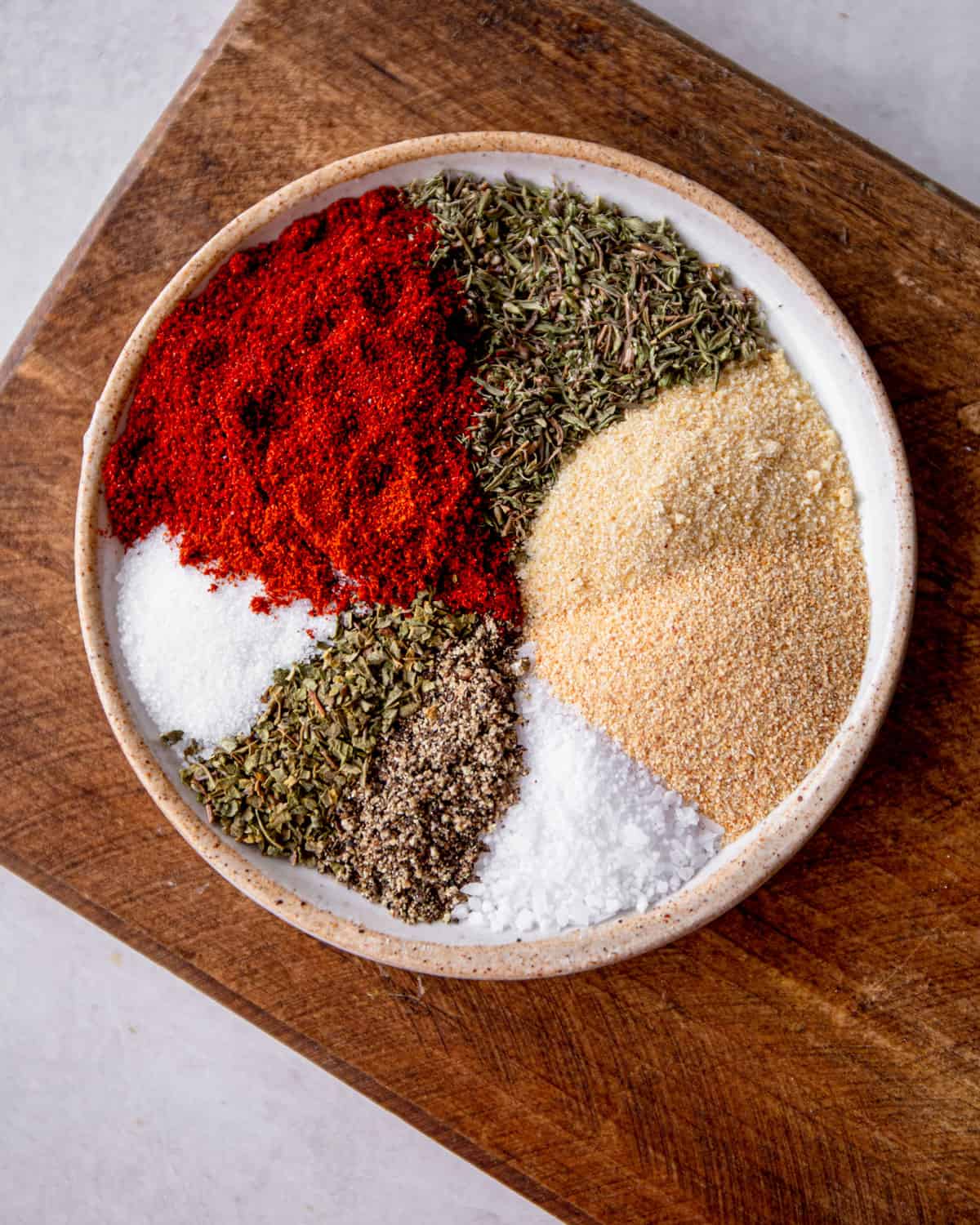 spices in a small tan bowl on a wooden cutting board