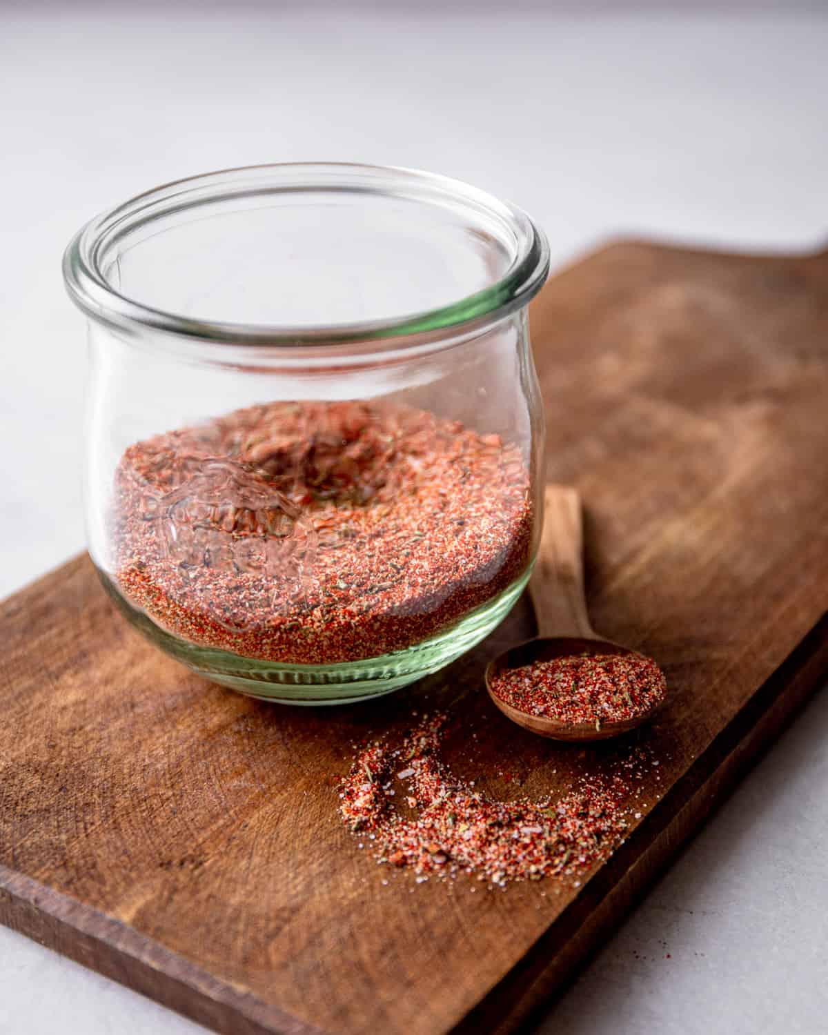 seasoning in a small glass jar on a wooden cutting board