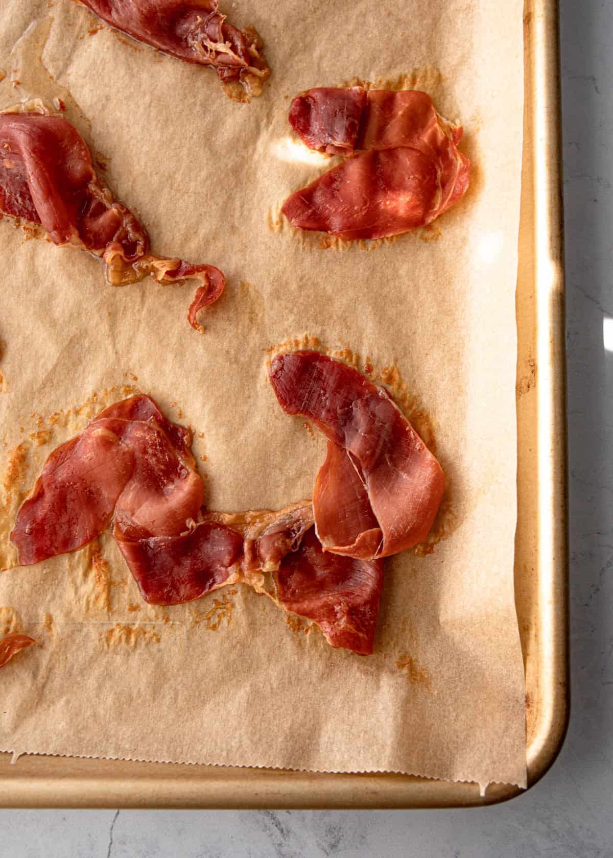 cooked prosciutto on a parchment lined sheet pan