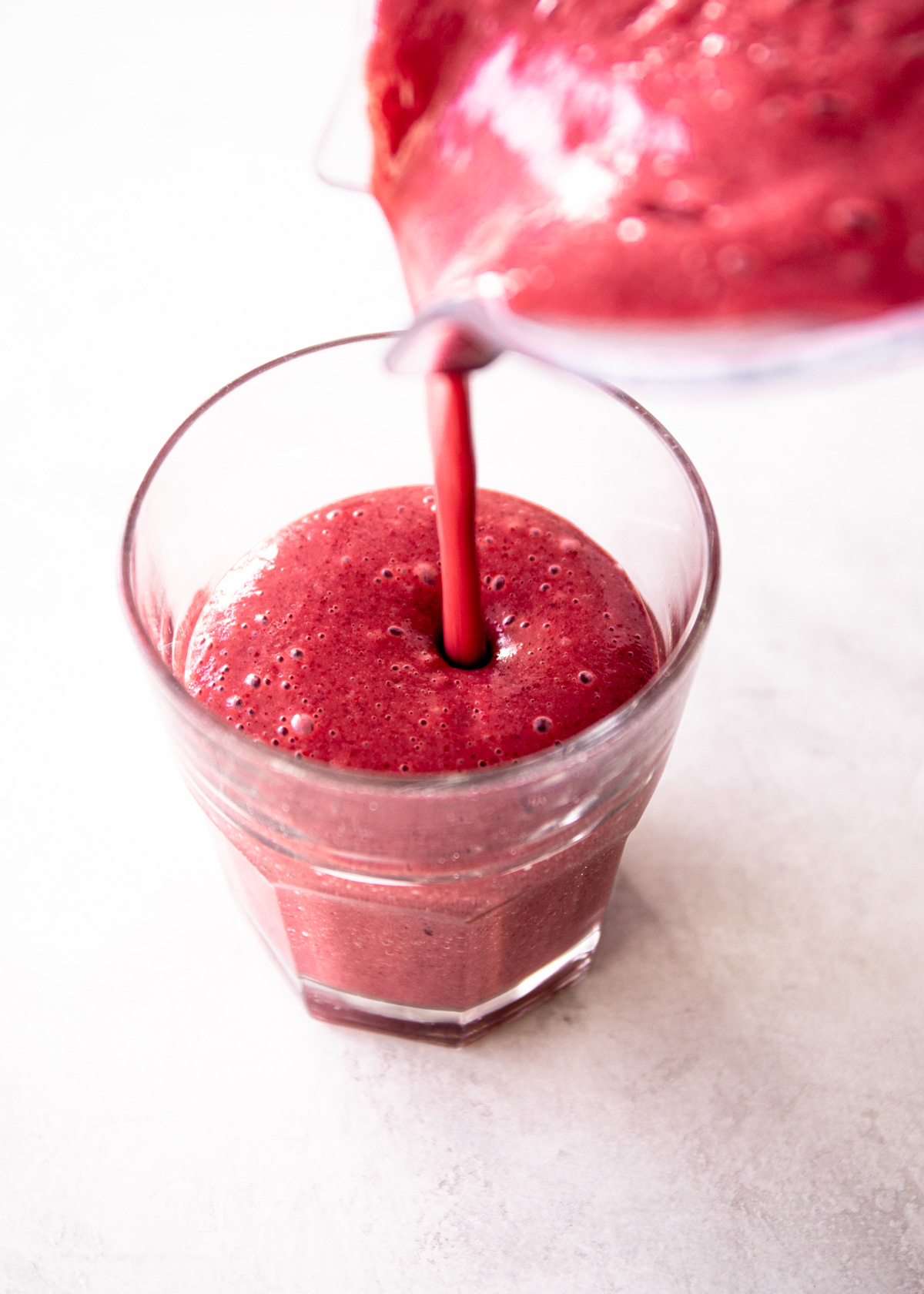 pouring smoothies from a blender into a glass