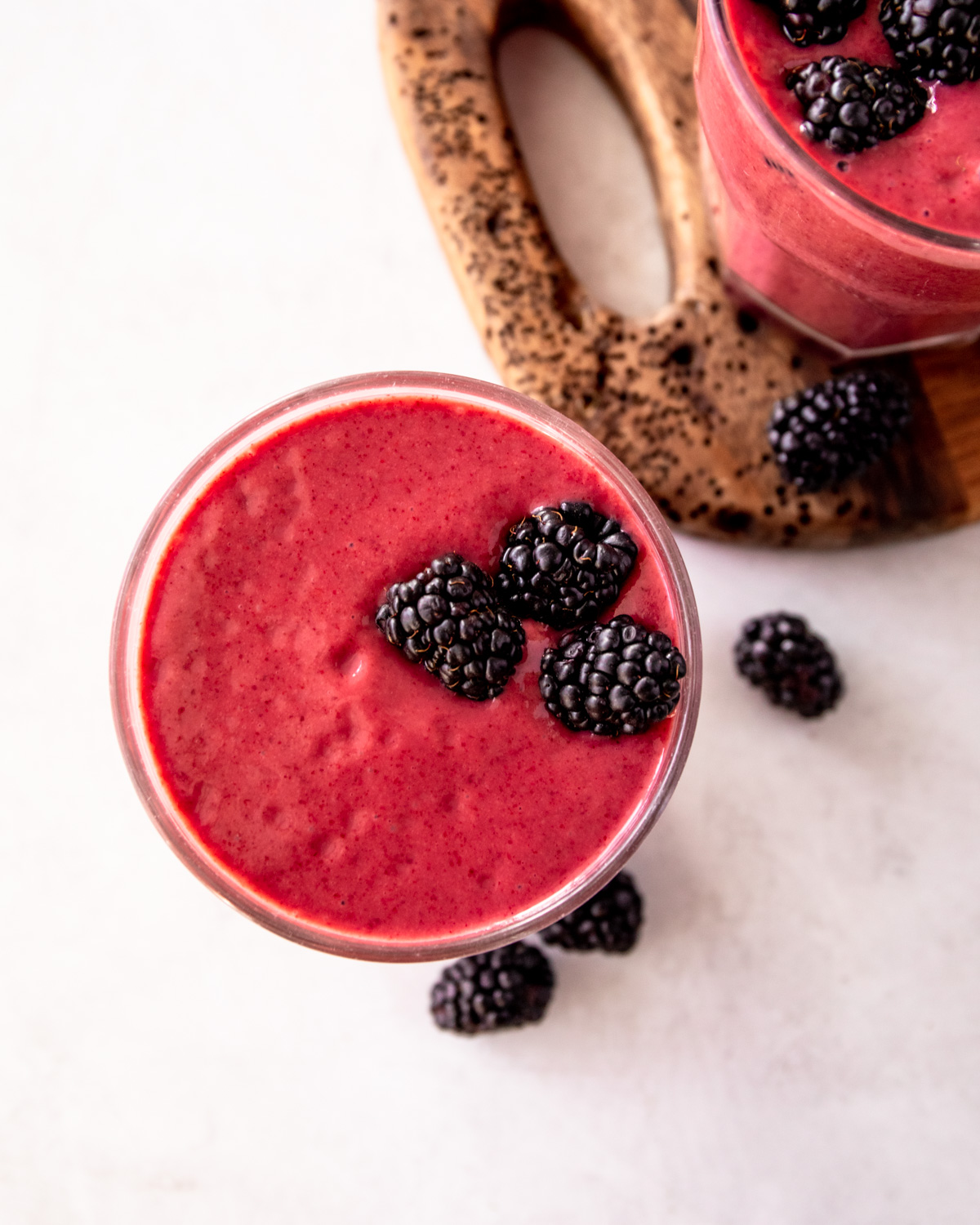 blackberry smoothie in a glass on a white countertop