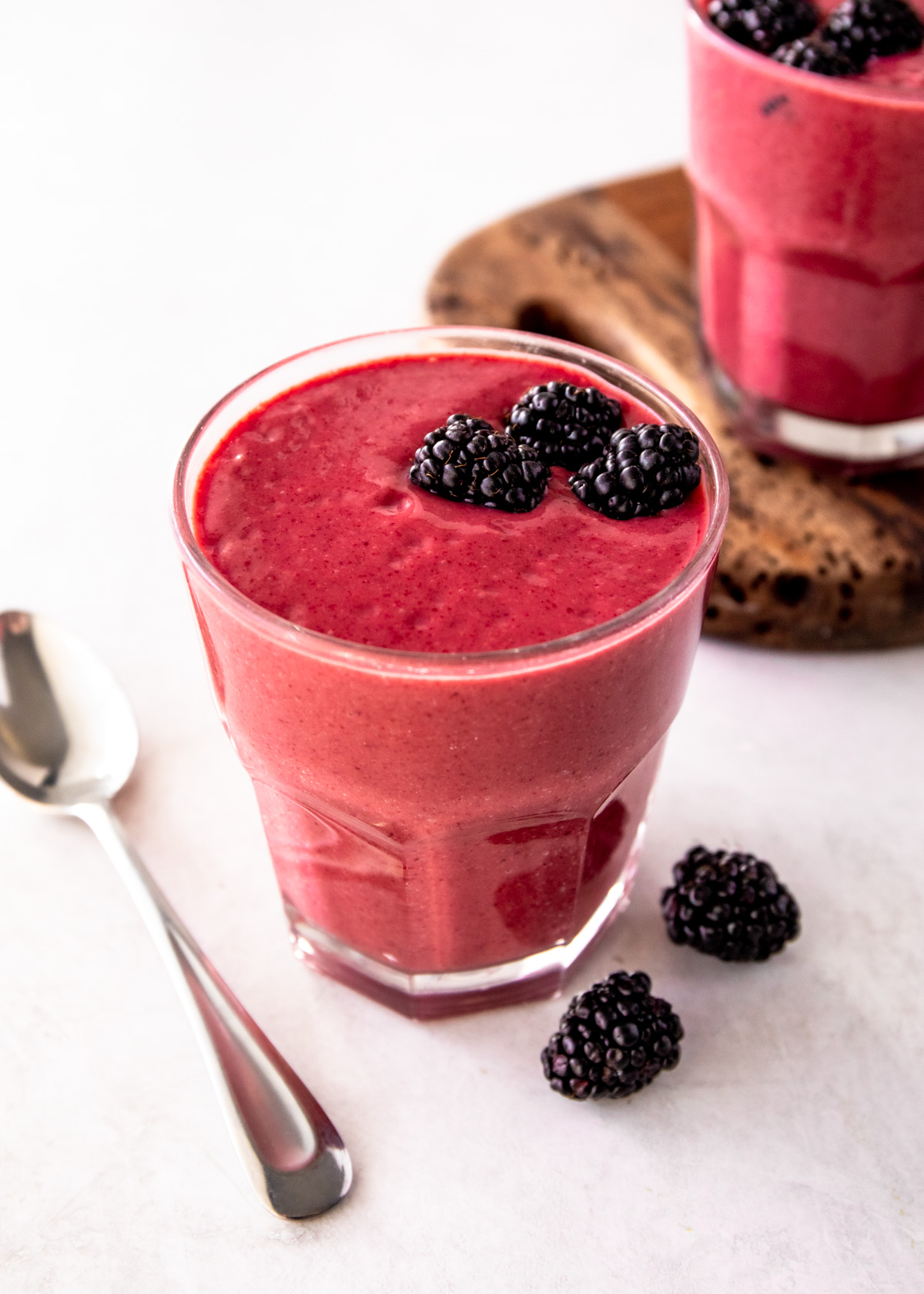 blackberry smoothie in a glass on a white countertop