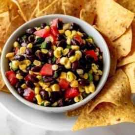 salsa in a white bowl next to corn chips on a white plate