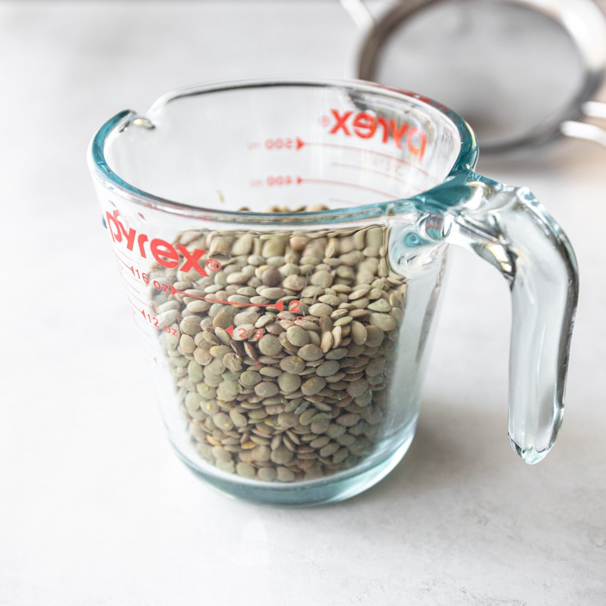 uncooked lentils in a clear glass measuring cup